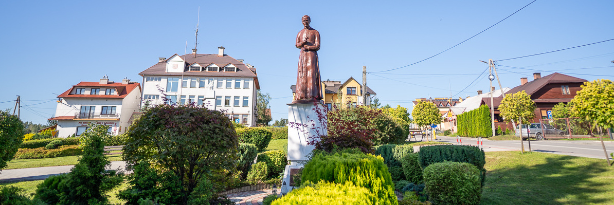 Pomnik św. Jerzego Popiełuszki, w tle Urząd Gminy Niebylec